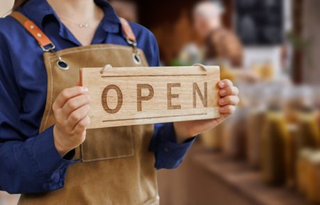 Farm shop owner holding an Open sign