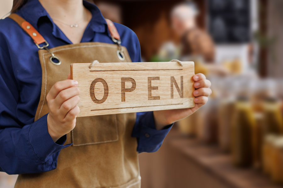 Farm shop owner holding an Open sign